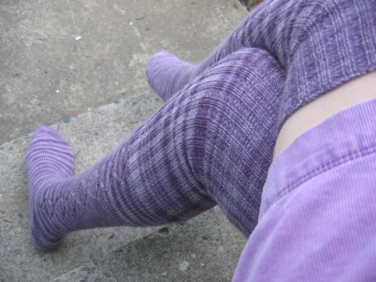 a person standing with her legs crossed wearing purple socks