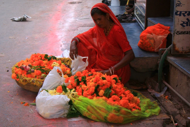 a woman sitting on a street arranging flowers