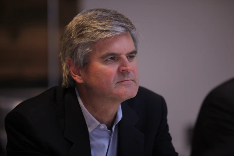 a man in a suit stares ahead while sitting