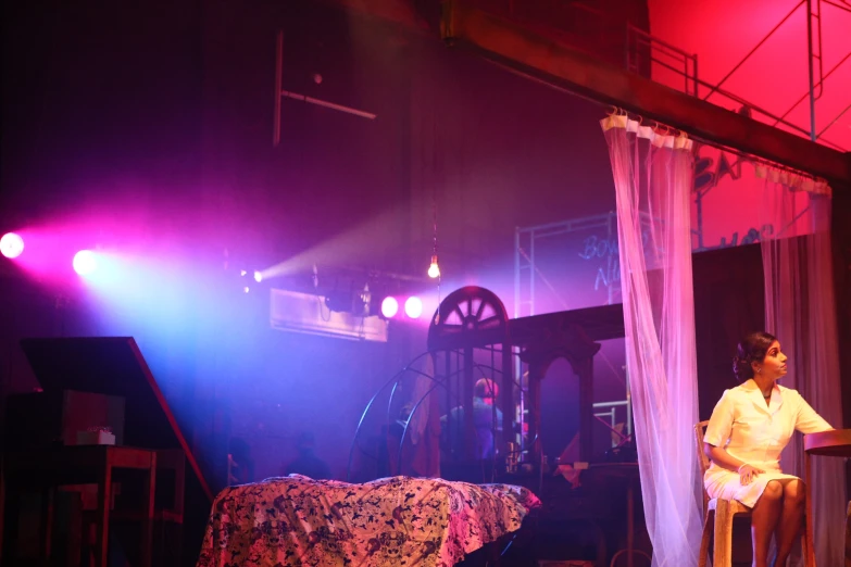 a woman sitting on top of a chair in a stage setting