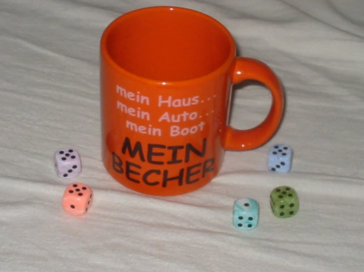 a ceramic orange mug with three dice and six sayings