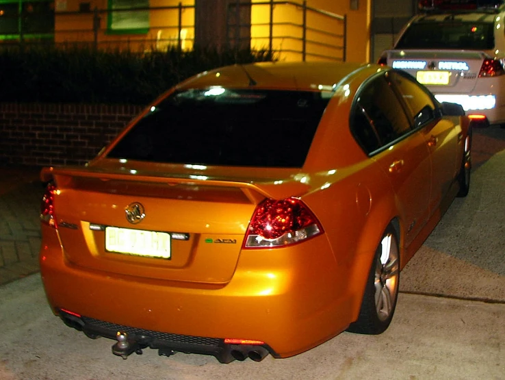 an orange car is parked on the side of a road