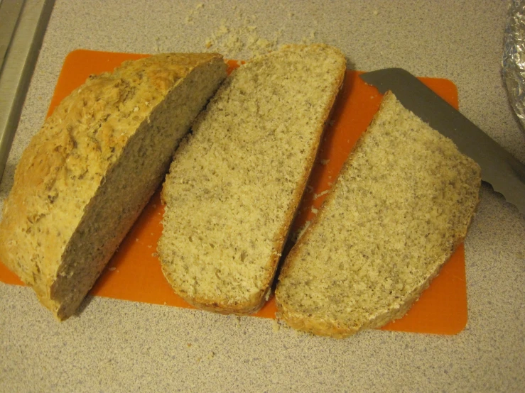 a loaf of bread sliced into four pieces on a plate with a knife