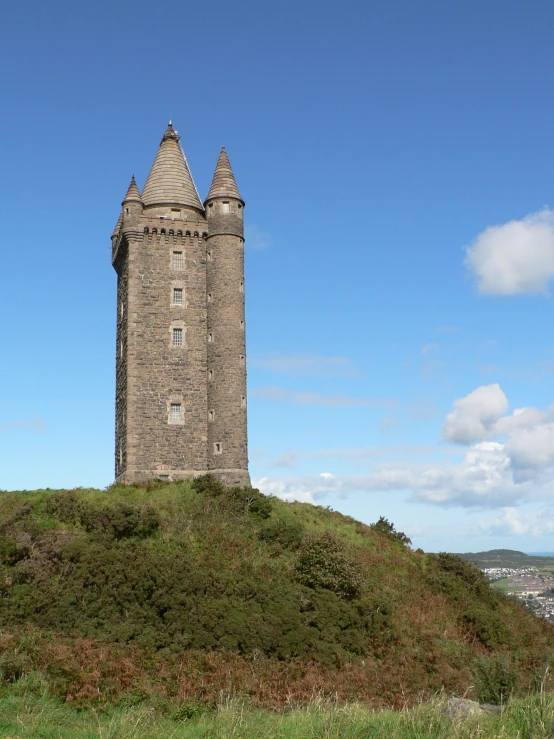 a clock tower sitting on top of a grassy hill