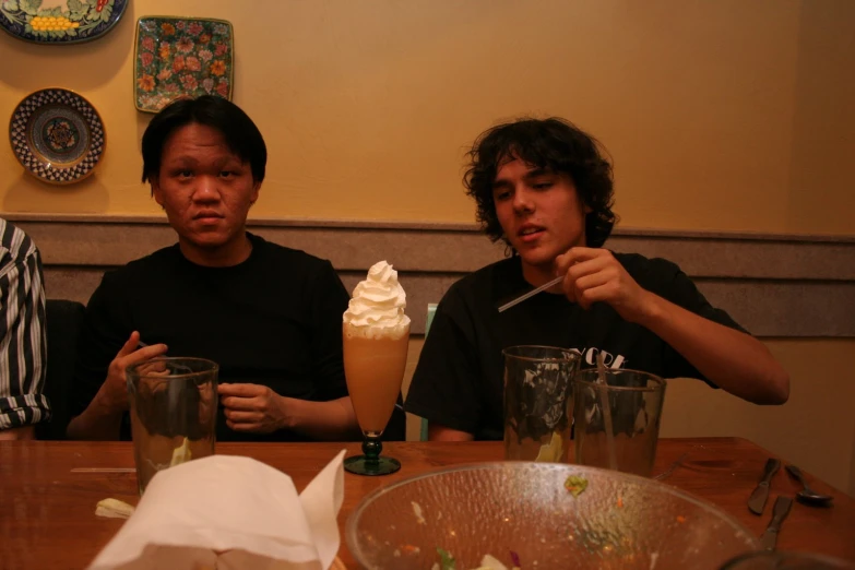 two men sit at a table with various drinks
