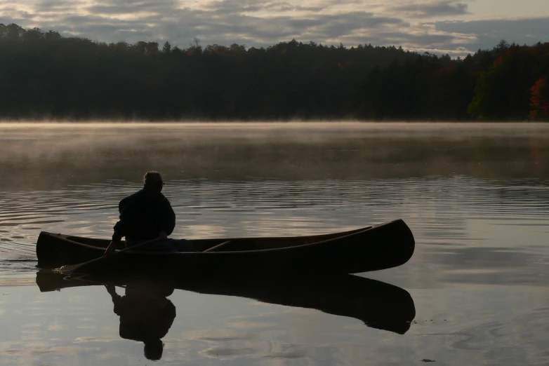 a person is sitting in the bow of a canoe on the water