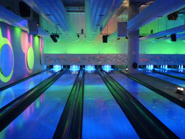 an indoor bowling alley with blue lighting at the end