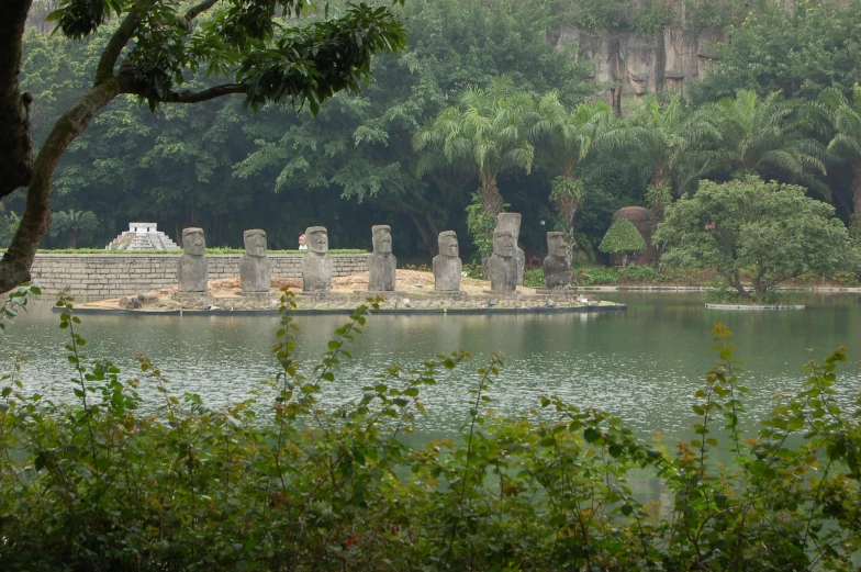 a body of water surrounded by trees and statues