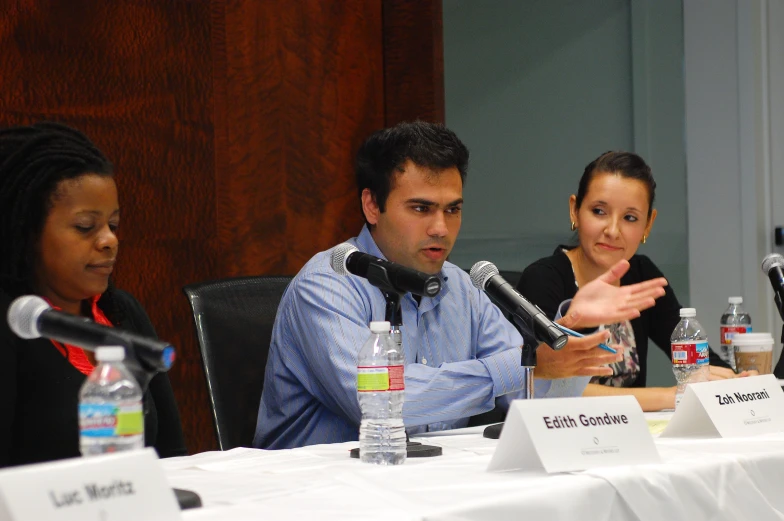 three people sitting in front of microphones talking