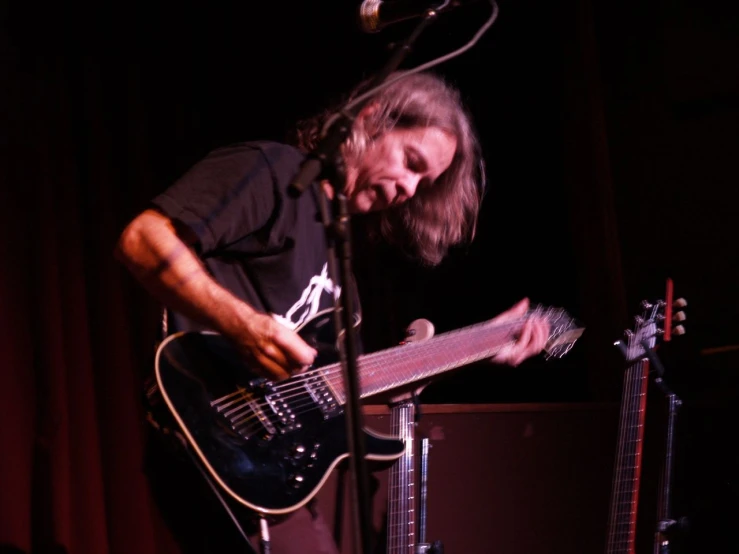 the guitar player with long hair plays his instrument