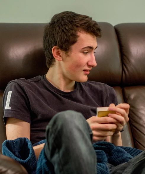 a young man sitting on the couch using his cellphone