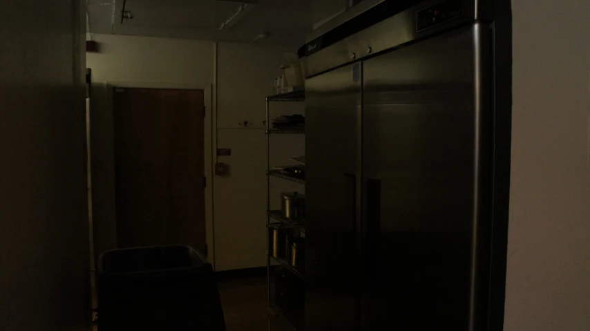 there is a refrigerator in the dark by a wall