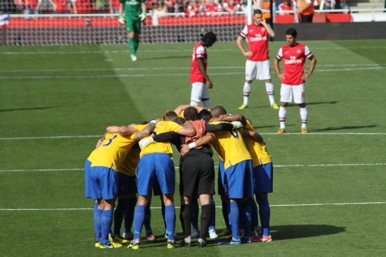 a group of soccer players huddle together on the field