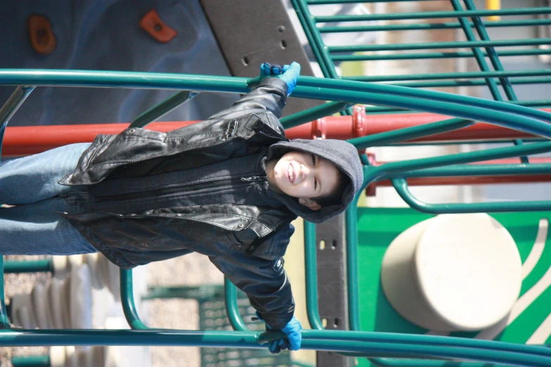 little girl in black jacket playing on a playground