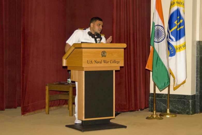 a man in military uniform giving a lecture on the stage