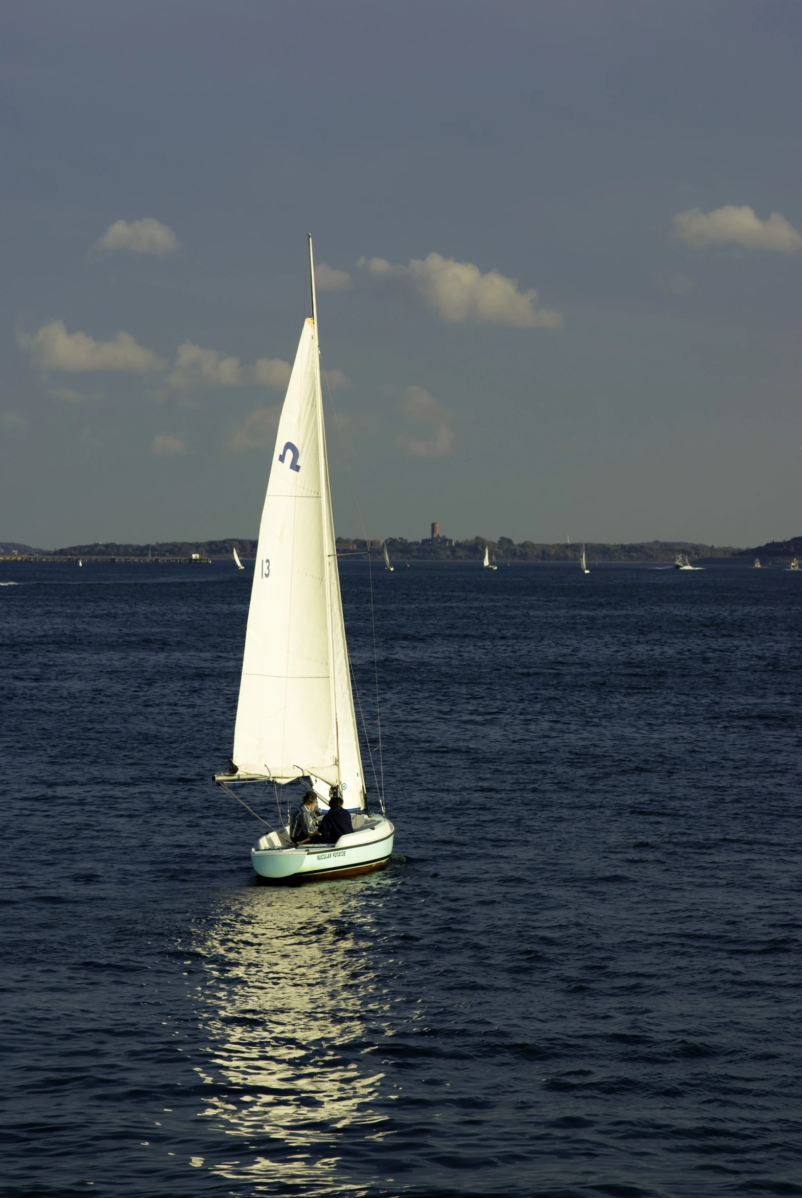 a sailboat sails on the water beneath cloudy skies