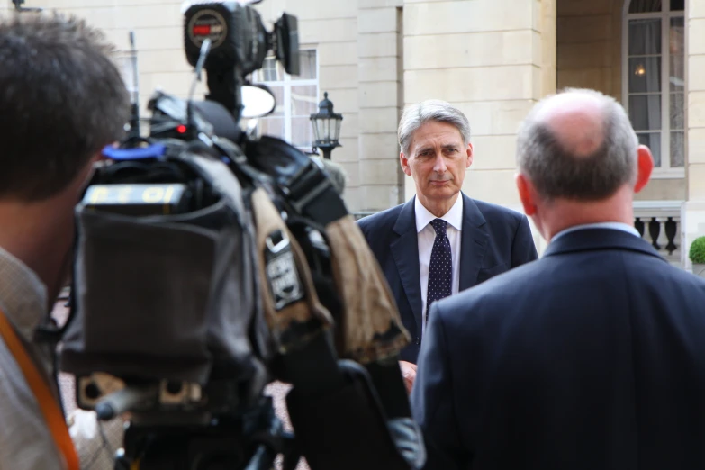 a man in suit and tie standing in front of some pographers