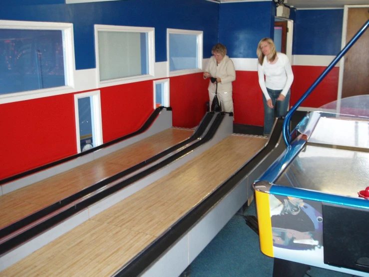 two women standing at a bowling alley area