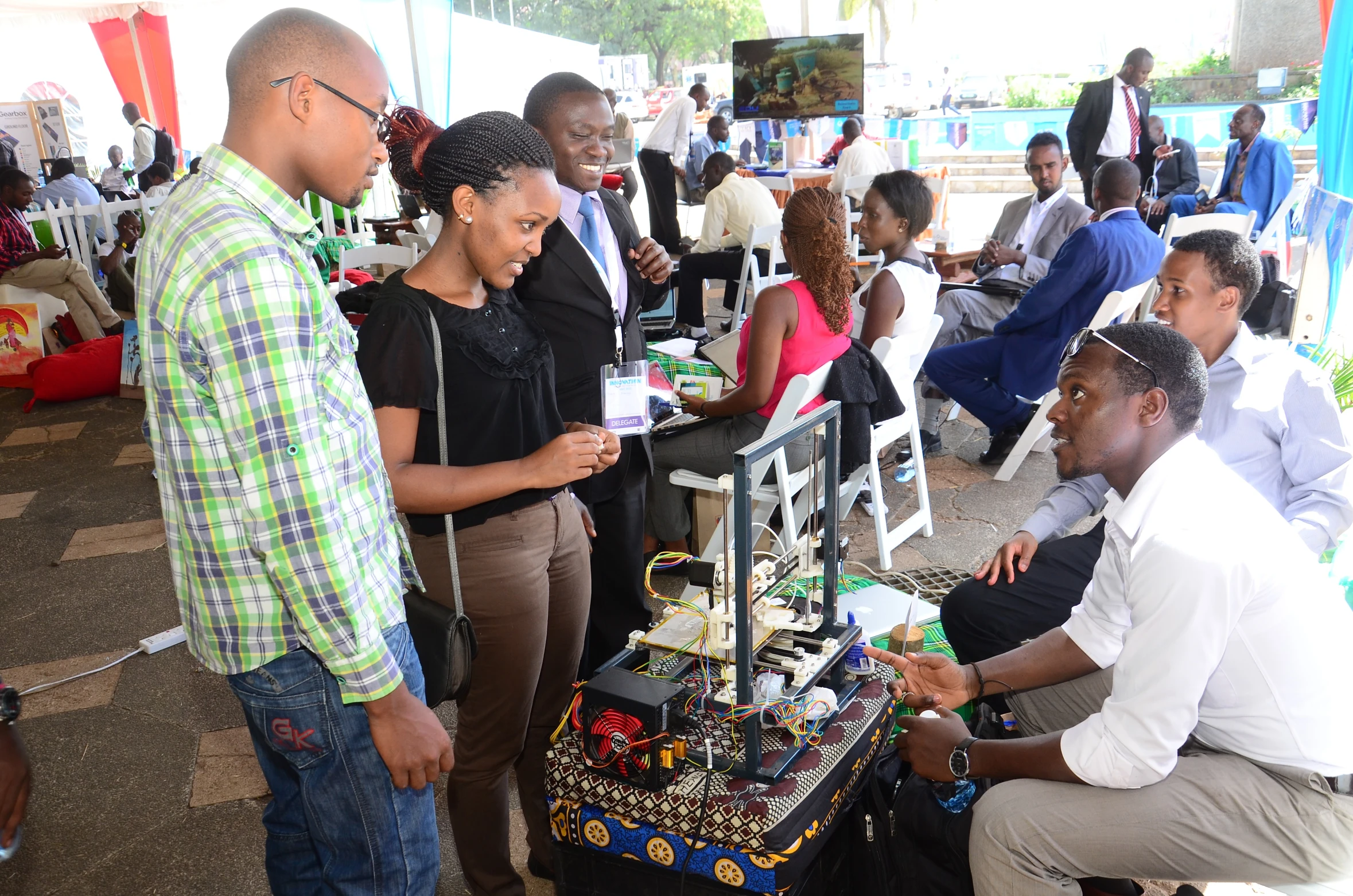 several people are sitting on chairs and looking at a robot model