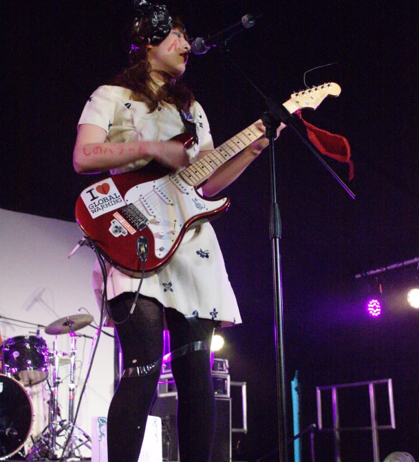 a woman standing on stage with an electric guitar