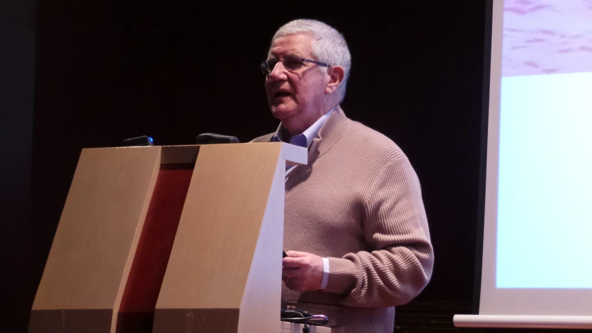 an older man is making his point while giving a speech