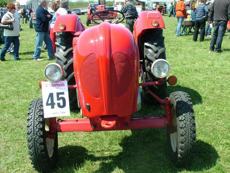 several people are standing around at an antique car show