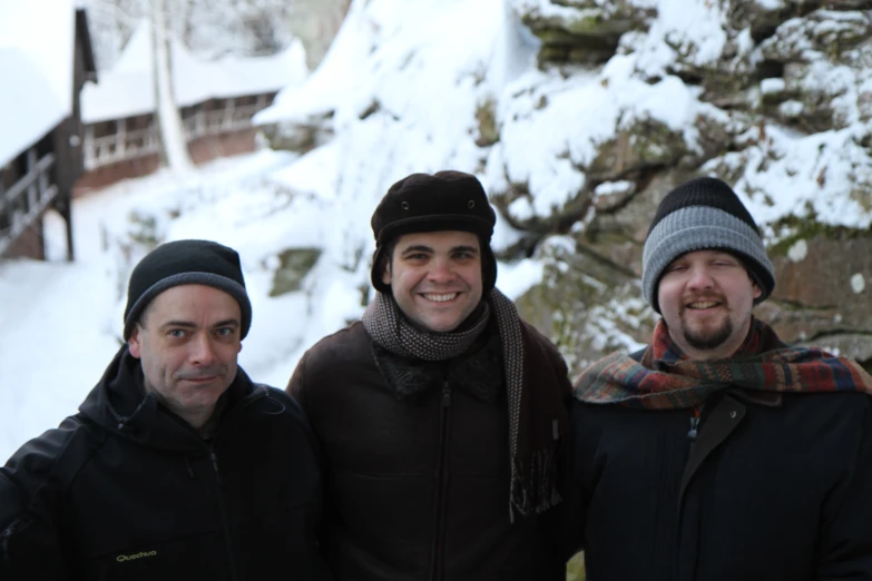 three men posing in front of snow covered mountains