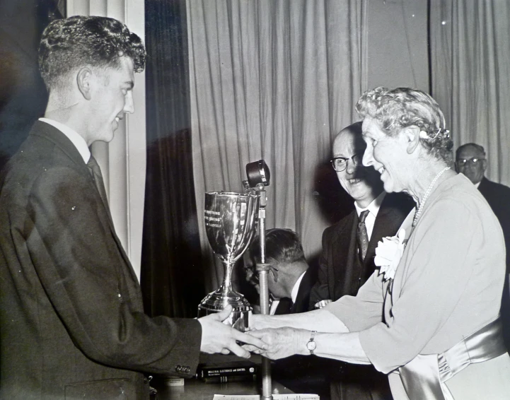 a man in a suit giving a woman a trophy