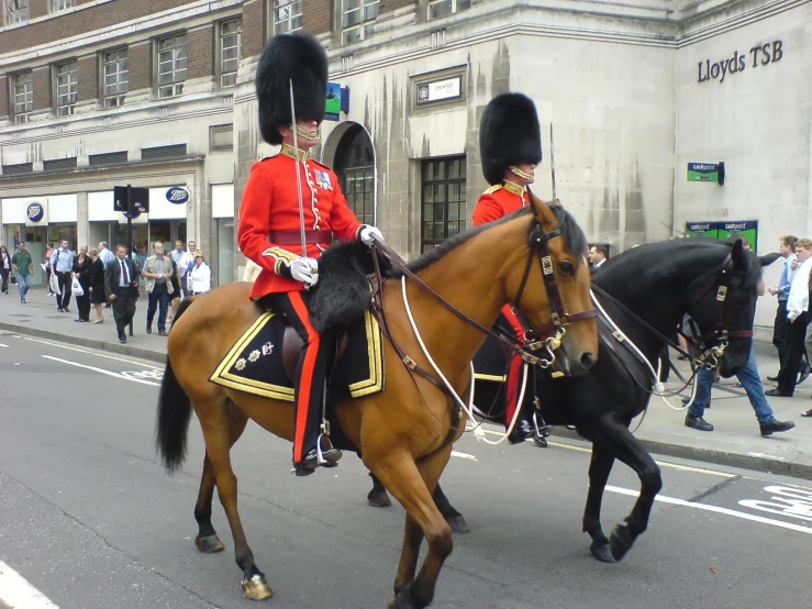 two men wearing military uniforms ride on horses in a parade