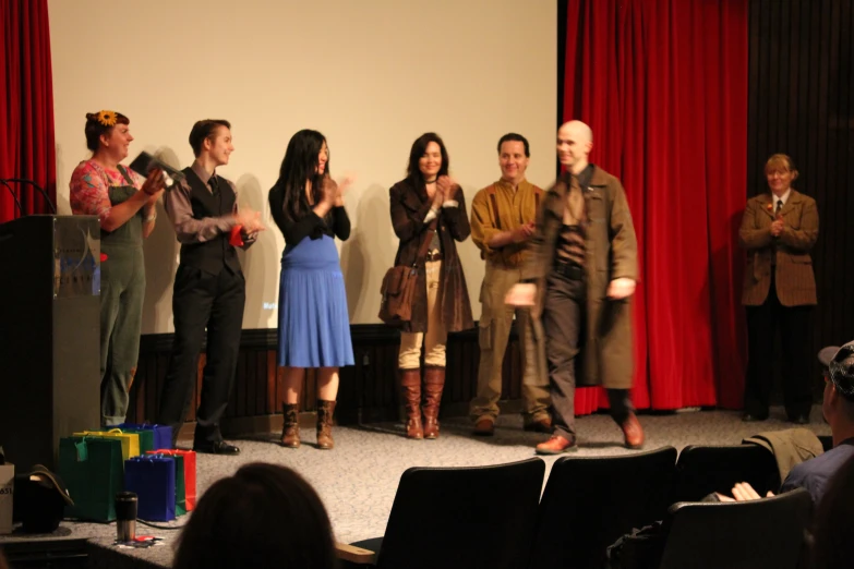 a group of people standing on stage in front of a curtain