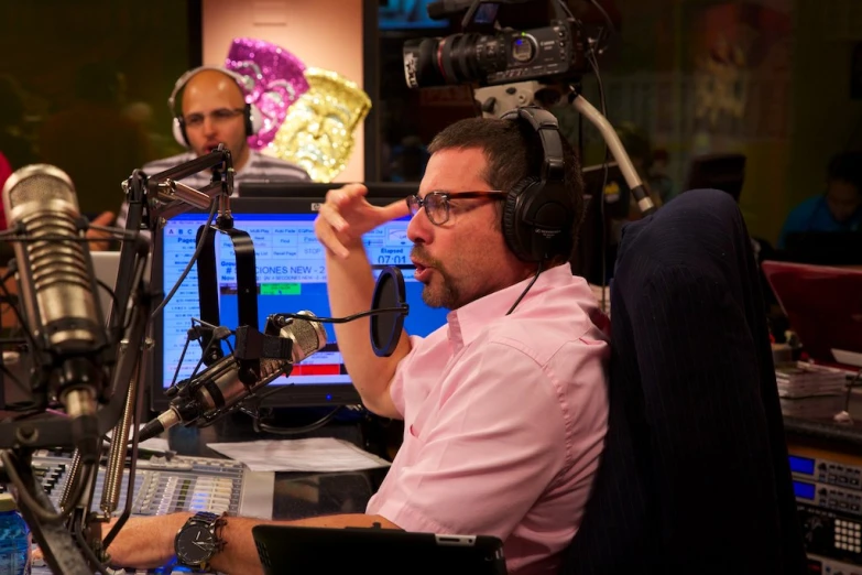 a man with headphones on sitting in front of a microphone