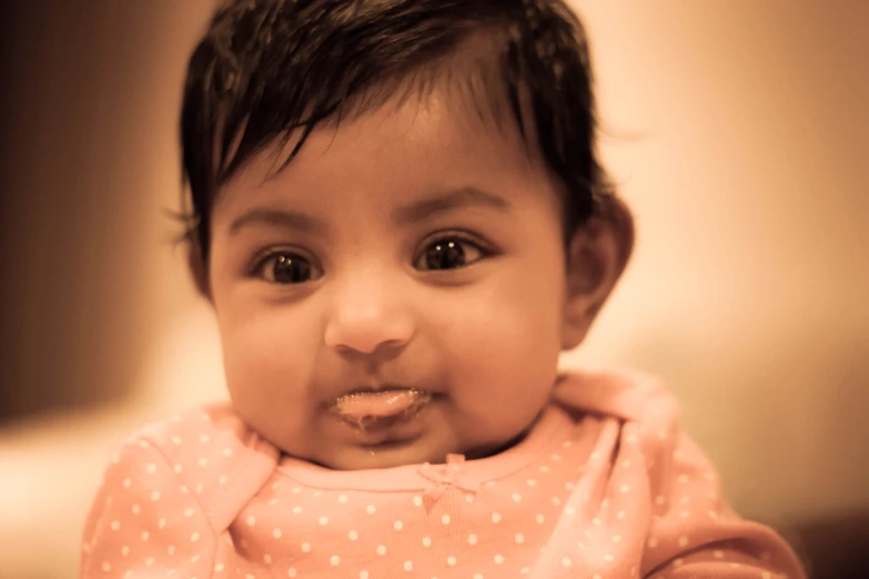 a close up of a baby girl making a face with a plastic spoon