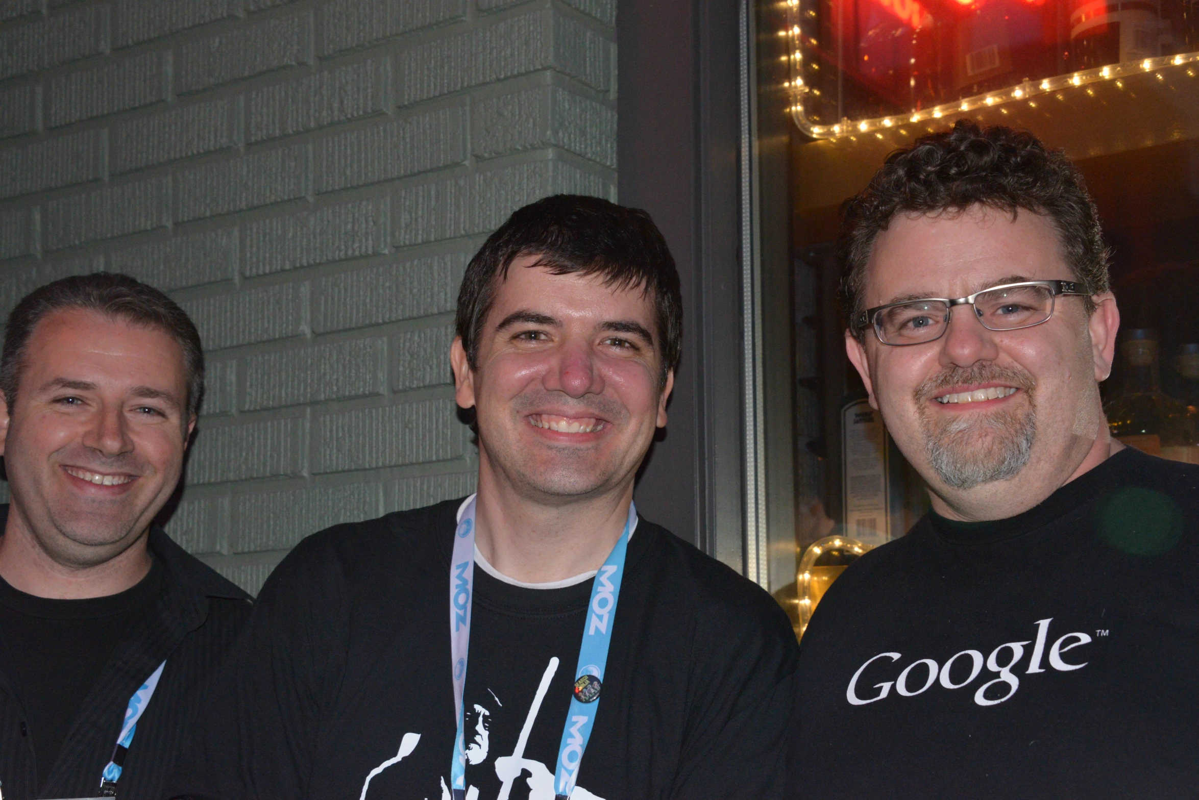 three men smiling and posing in front of a window