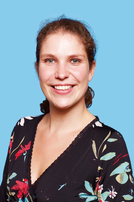 woman in black top standing by blue wall smiling