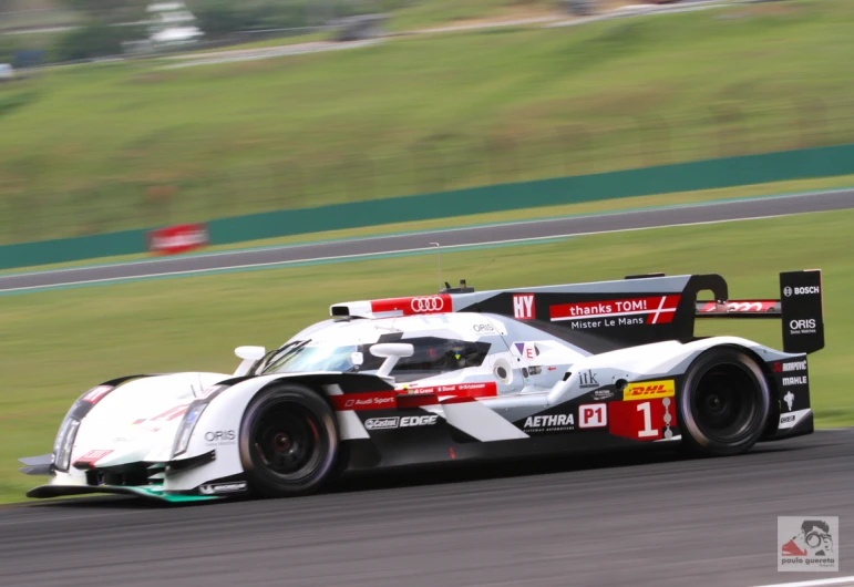 a race car racing on the track near grass