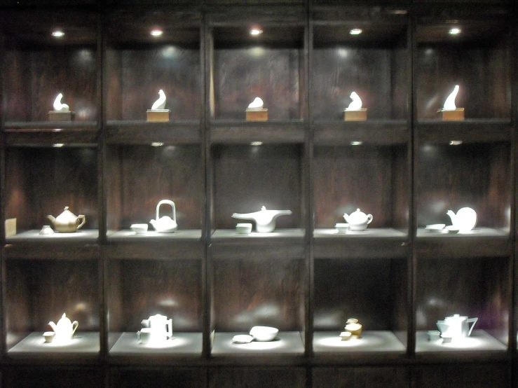 a wall full of various kinds of teapots