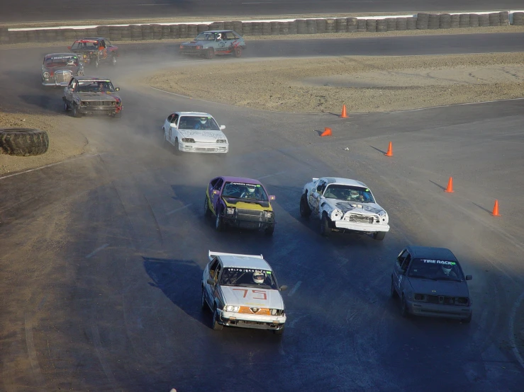 several cars going through a race with smoke pouring from the tires