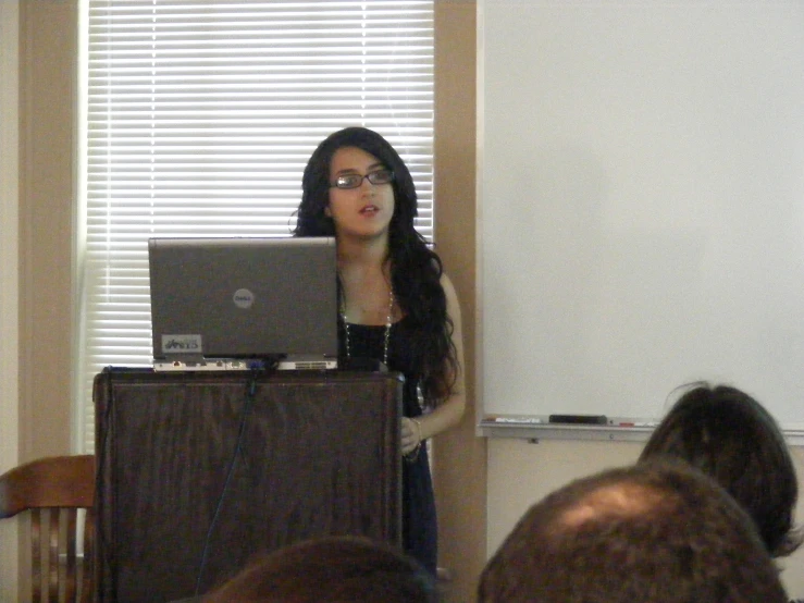 the woman is standing near the laptop in front of the audience