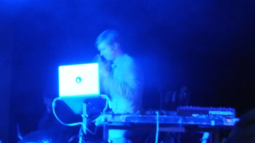 a dj with laptop in his hand at a night concert