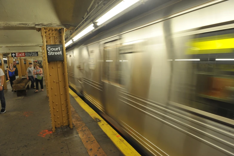 a train that is running by a platform with some people watching it