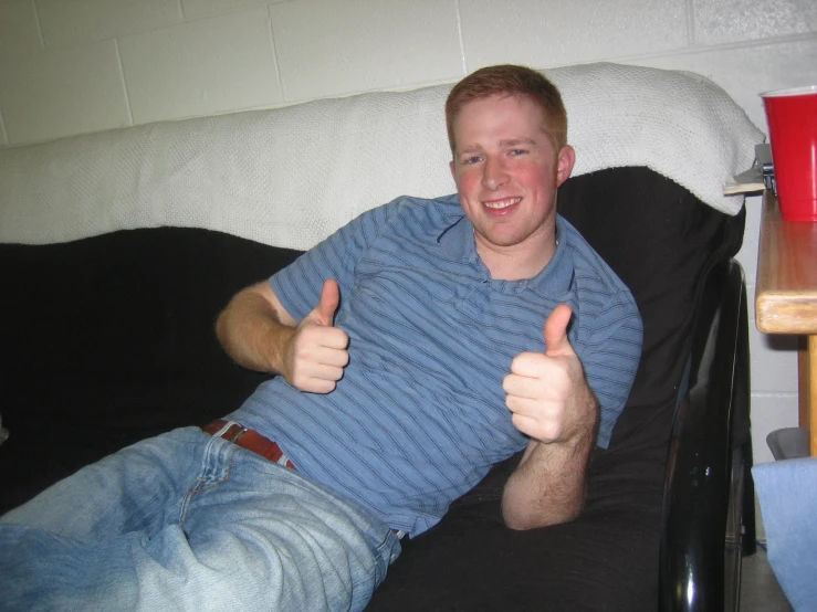 man sitting on couch holding thumbs up giving thumbs up