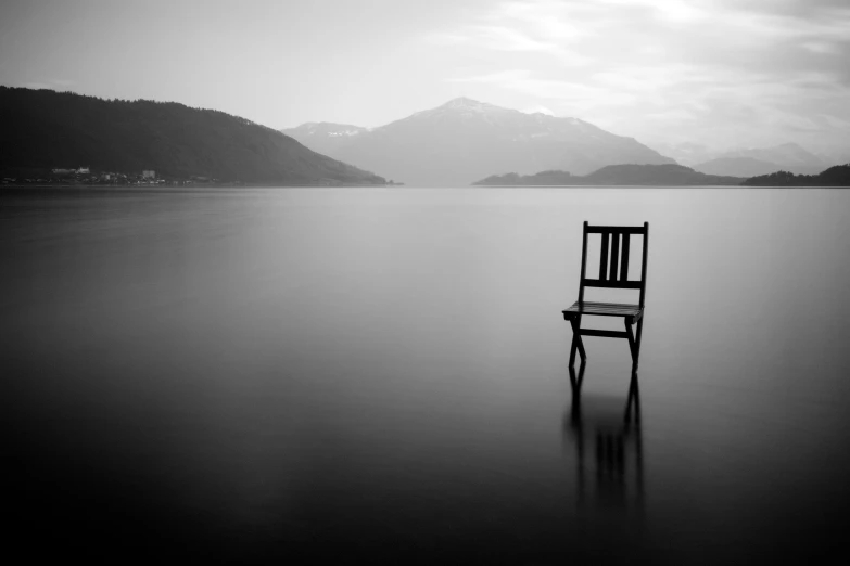 a lone chair in the middle of a large body of water