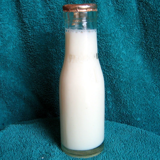 a bottle of milk is seen sitting on a green cloth