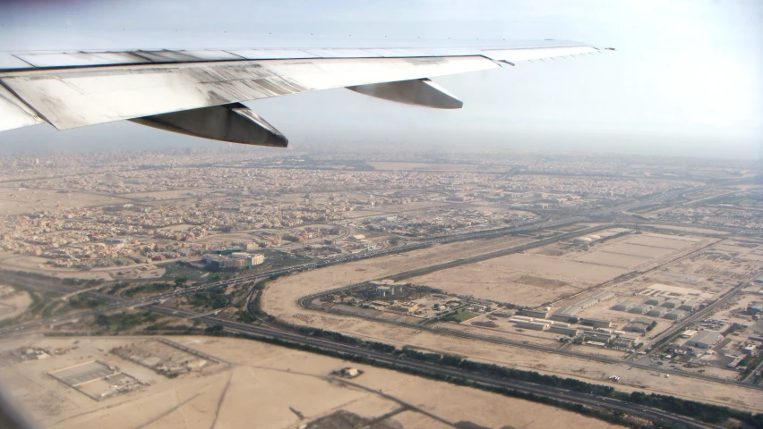 the view out of an airplane window shows a highway and a city