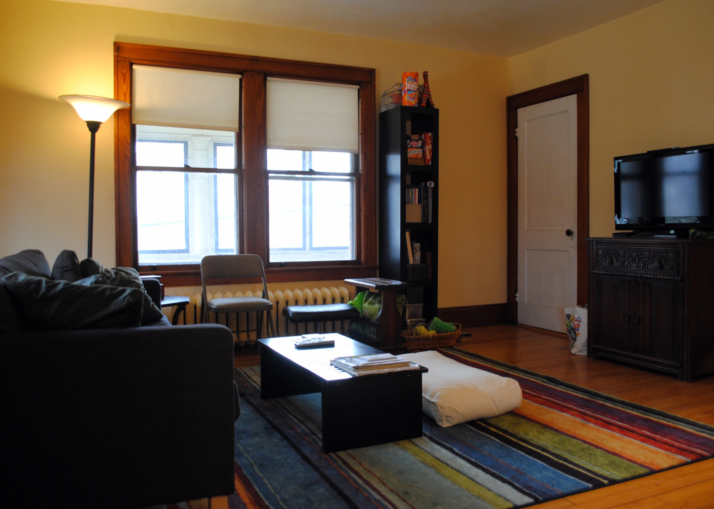 a room with wooden floors, two windows and couches