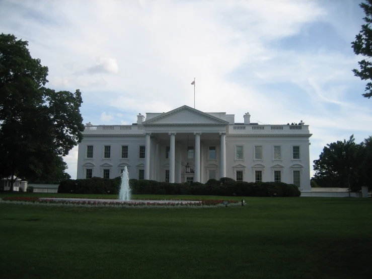 an old white house with trees and a fountain