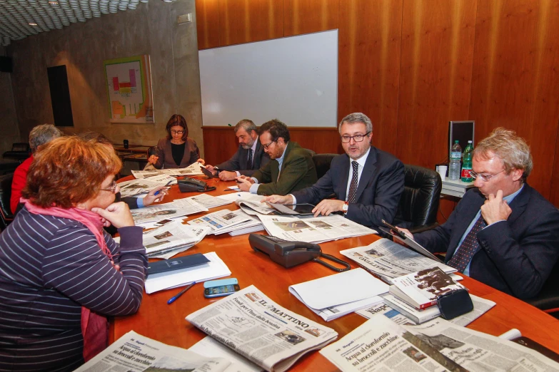 several people sitting around a conference table looking at papers