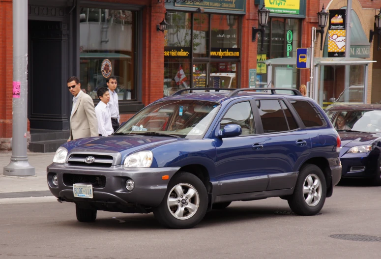 two men walk down a street beside several cars