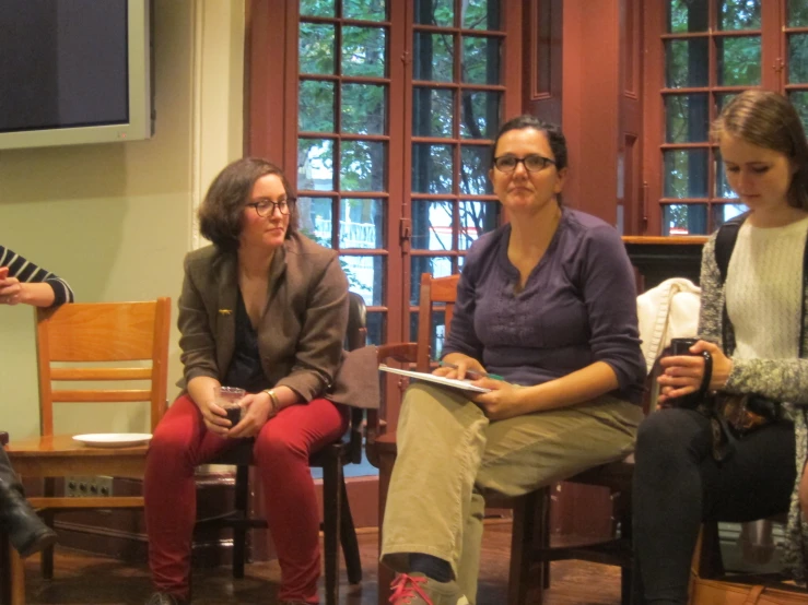 three woman sitting in a line with papers