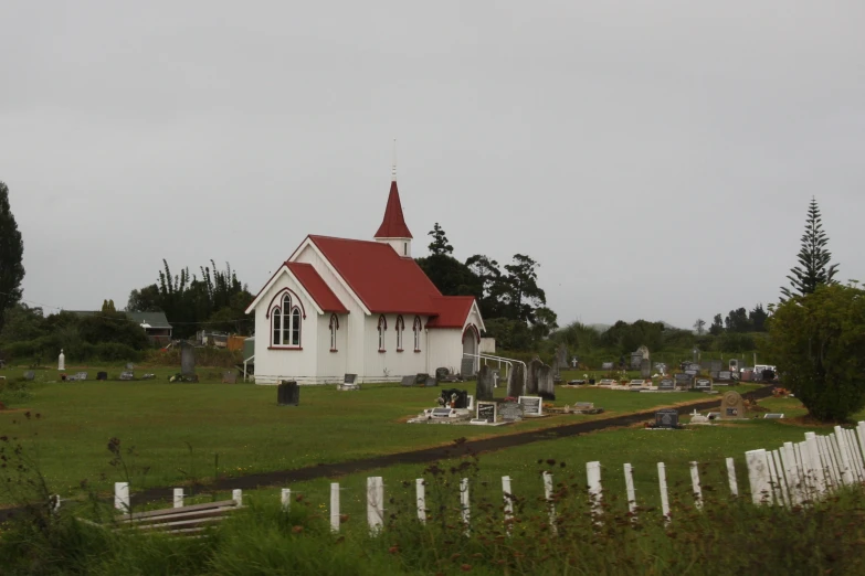 a red and white church with cemetery in the background